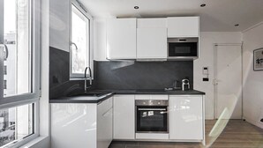 Una cocina moderna con armarios blancos, encimera negra, horno empotrado y microondas.