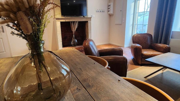 Uma sala de estar moderna com uma mesa de jantar de madeira, sofás de couro, lareira e televisão.