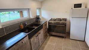 Cozinha compacta com fogão a gás, forno embutido, micro-ondas e pia.