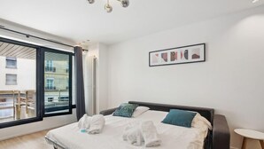 A modern hotel room with a large bed, a view of the outside balcony, and a small round table. - 174 Suite Grenelle - Marvelous apartment in Paris (Paris 15 Vaugirard)
