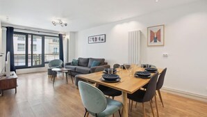 A modern living room with a dining area, large windows, and a view of buildings outside. - 174 Suite Grenelle - Marvelous apartment in Paris (Paris 15 Vaugirard)