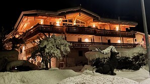 Ein mehrstöckiges Hotel mit Balkonen, verschneiter Umgebung und warmer Beleuchtung.
