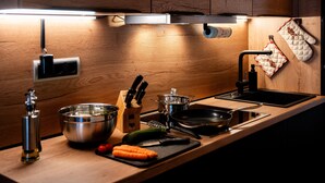 Eine moderne Küche mit Holzschränken, Edelstahlgeräten und einer schwarzen Arbeitsplatte.