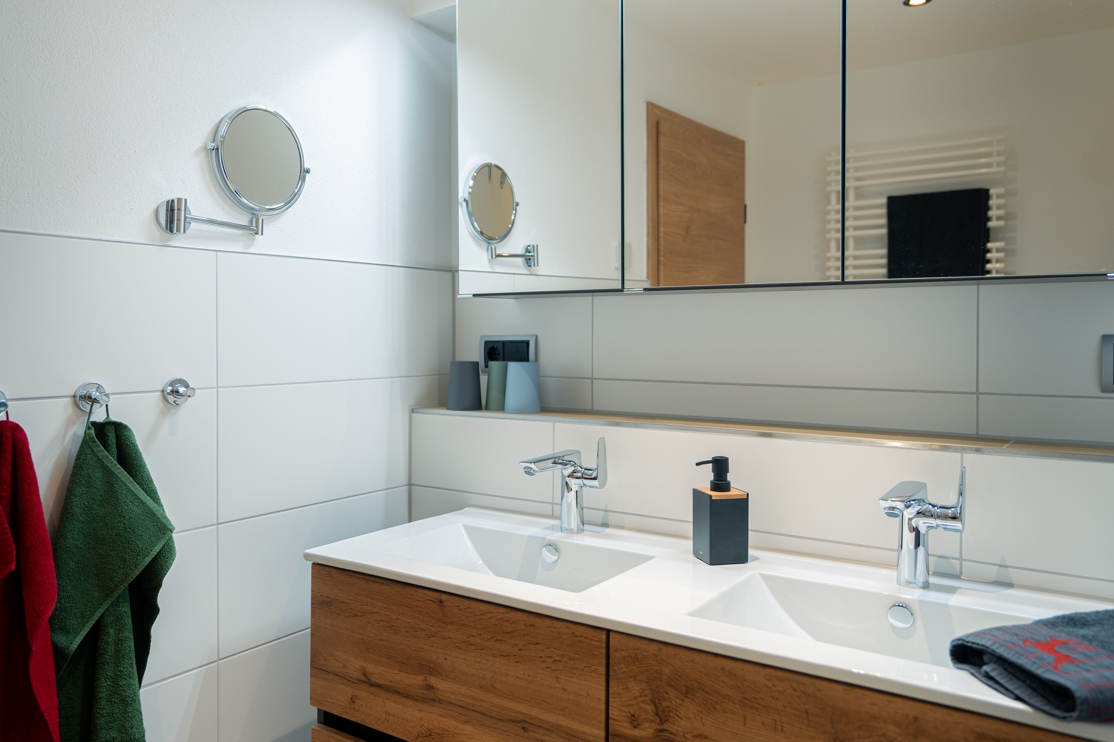 Ein Badezimmer mit zwei Waschbecken, einem Spiegel und einer Holz-Kommode.