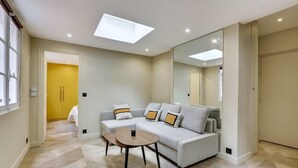A modern living room with a sofa, a coffee table, and a large mirror. - 170 Suite Z - Superb apartment in Paris. (Paris 02 Bourse)