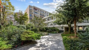 En bostadsbyggnad med en stenlagd gångväg som omges av grönska.