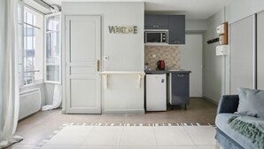 A compact kitchen with a microwave, a small refrigerator, and a coffee maker. There is a 'WELCOME' sign on the wall, and a sliding door leading to a balcony. - 258 Suite Orsel - Superb apartment in Paris (Paris 18 Buttes-Montmartre)