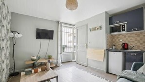 A compact living space with a kitchenette, a flat-screen TV, a sofa, and a dining table. - 258 Suite Orsel - Superb apartment in Paris (Paris 18 Buttes-Montmartre)
