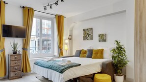 A modern bedroom with a bed, bedside tables, a TV, and a window with curtains. - 215 Suite Esprit Nature - Superb apartment (Paris 02 Bourse)