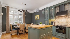 Una cocina con isla central, suelo de madera y una zona de comedor con sillas de mimbre.