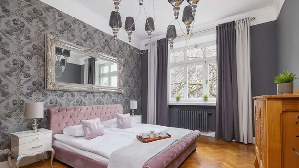 Un dormitorio con una cama grande, un aparador, una mesita de noche, un espejo y una ventana con cortinas.