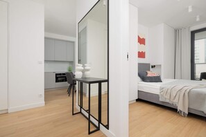 Ein modernes Schlafzimmer mit Bett, Nachttisch und Blick auf die Küche.