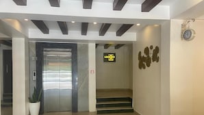 En moderne lobby med reception, et ur og en elevator.