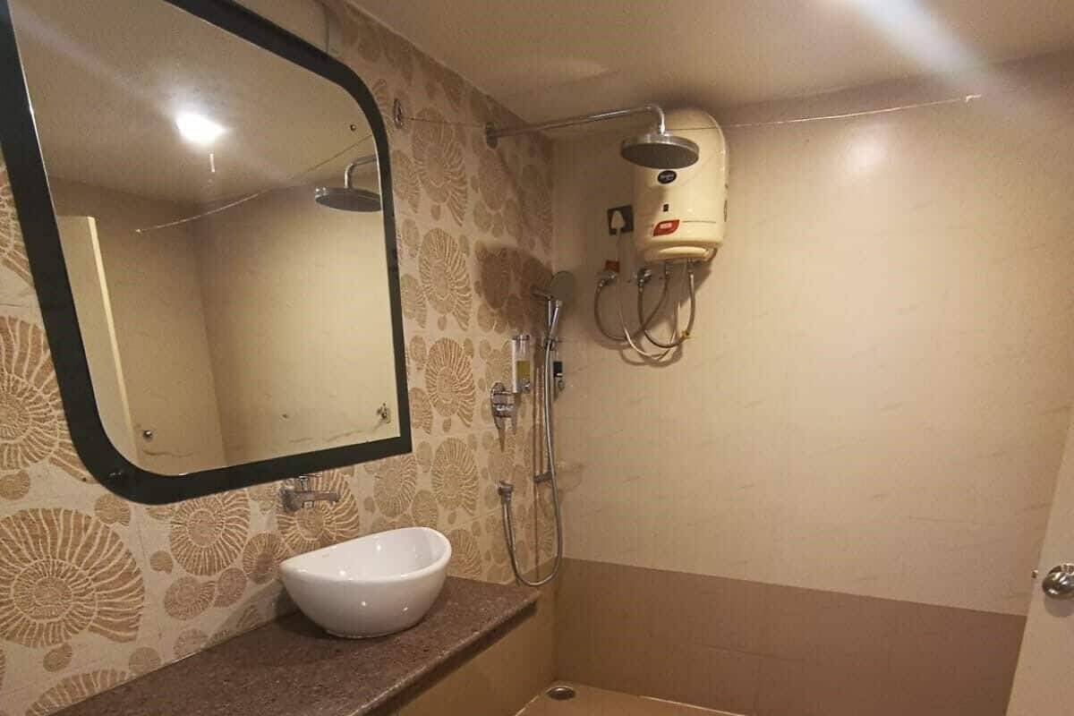 Un baño con lavamanos blanco, un espejo, ducha e inodoro.
