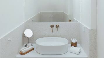A modern bathroom with a round sink, a mirror, and a towel rack.