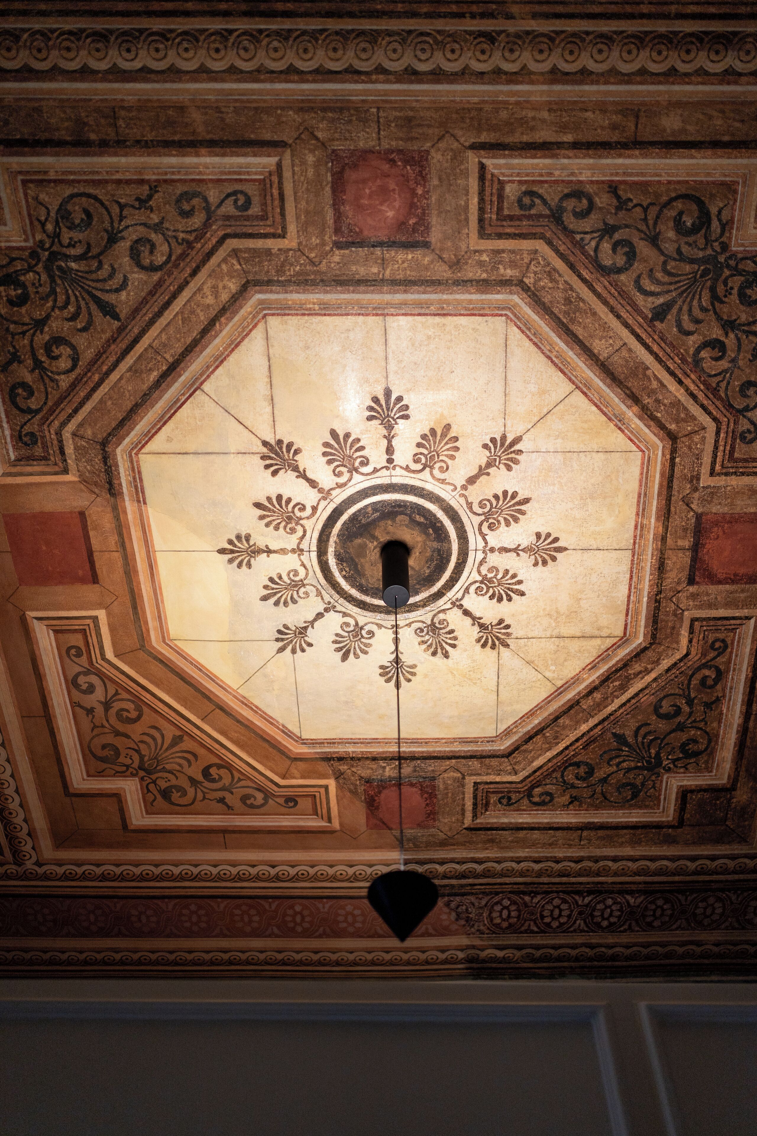 A ceiling with a central octagonal design featuring a circular motif and decorative patterns.