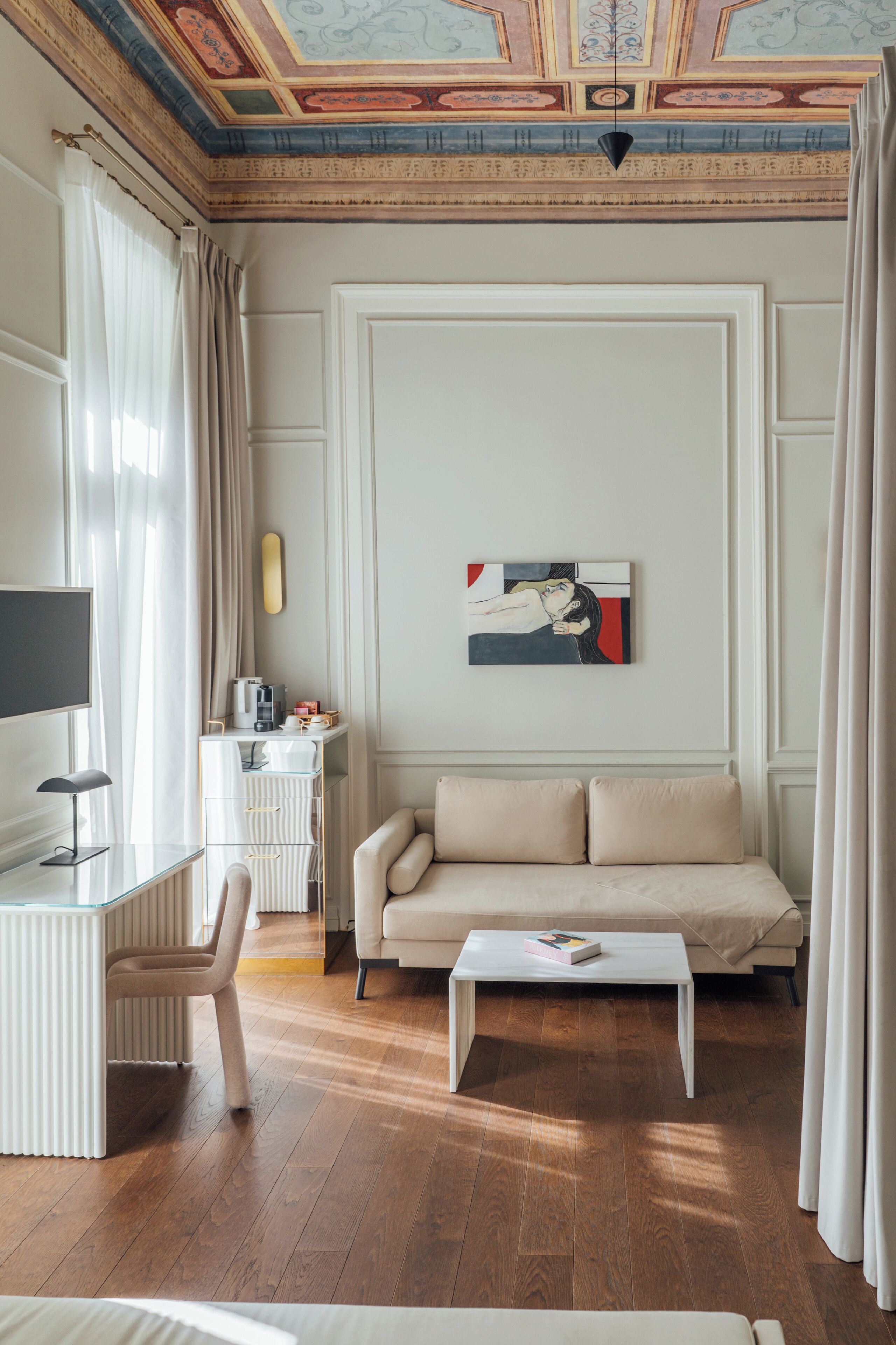 Un soggiorno moderno con divano, tavolino e un quadro appeso al muro.