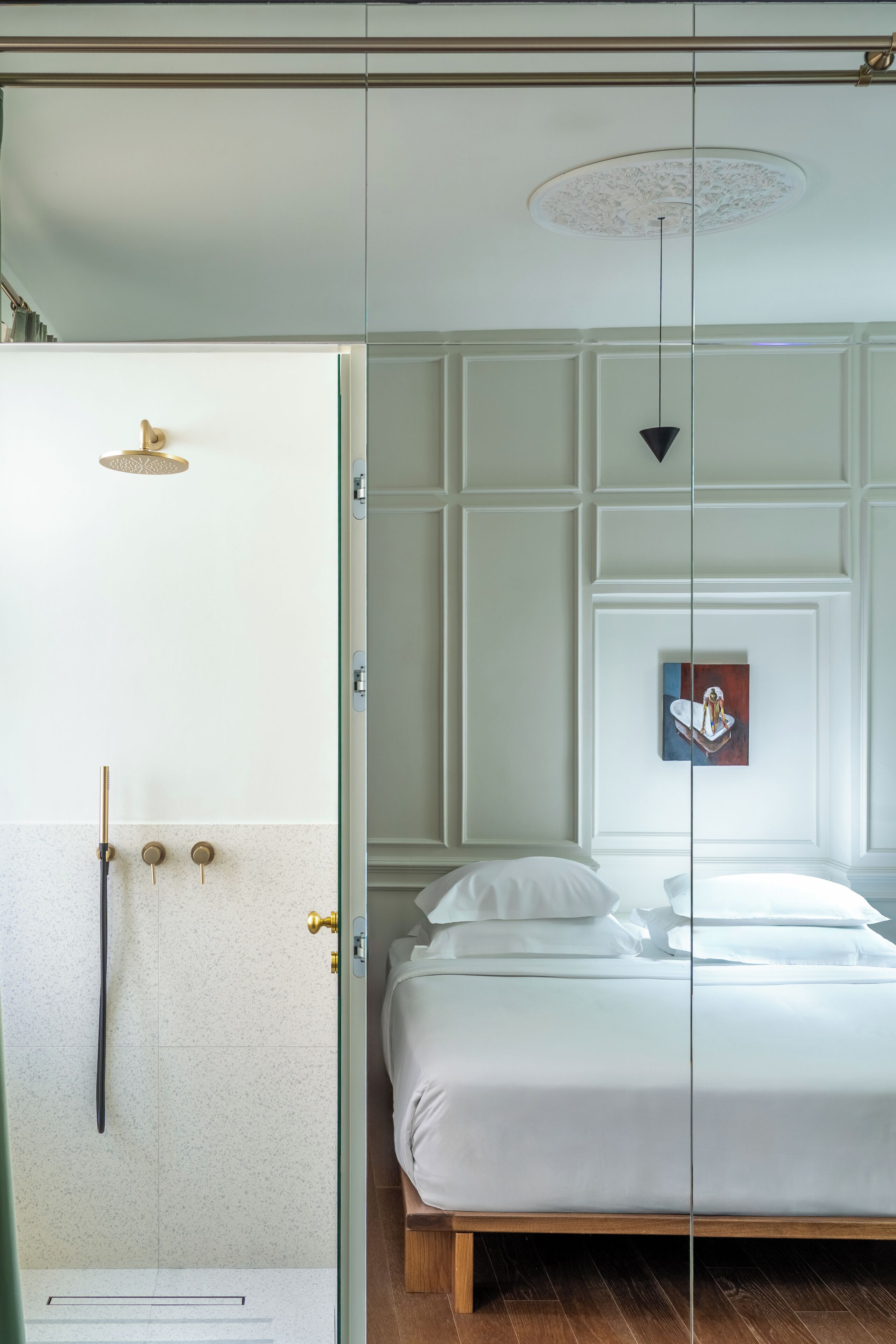 A bedroom with a bed, a shower, and a painting on the wall.