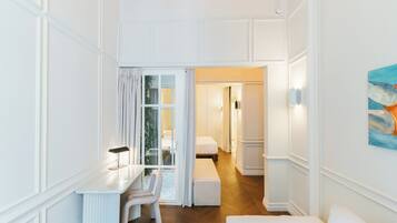 Habitación de hotel moderna con una decoración en blanco, un escritorio con lámpara, un banco y un cuadro en la pared.