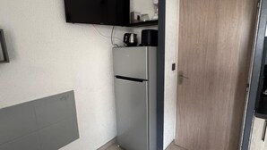 A compact kitchen with a built-in refrigerator, a microwave, and a coffee maker on the countertop.