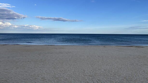 A beach with a clear sky and calm sea.