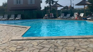 A swimming pool with lounge chairs and a building in the background.