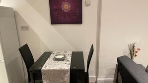 Una zona pranzo con tavolo, sedie, una panca, un vaso di fiori e un quadro appeso al muro.