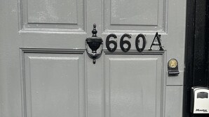 Una porta grigia con il numero 660A, una cassetta delle lettere nera e un campanello.