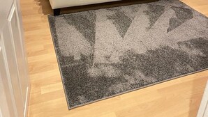 Una camera da letto con un letto, comodini, un armadio e un tappeto grigio.