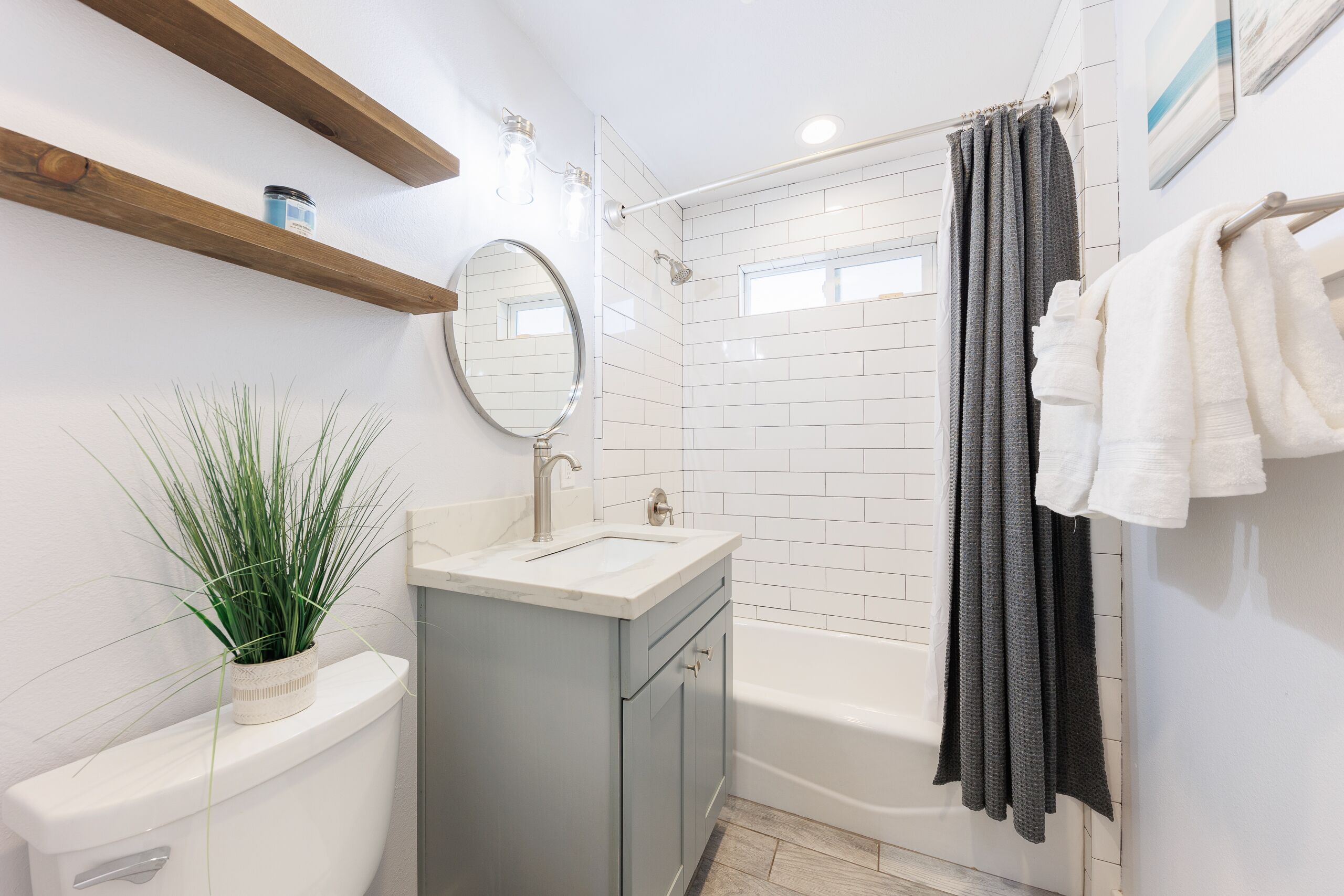 Een badkamer met toilet, wastafel, spiegel, douche en handdoekrek.