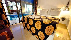 A hotel room with a large bed, a view of a swimming pool, and a balcony. - Villa das Arabias (Maputo)