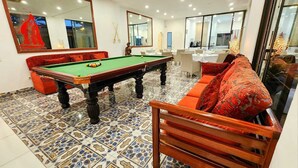 A billiards room with a pool table, a sofa, and a dining area with tables and chairs. - Villa das Arabias (Maputo)