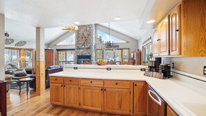 A spacious kitchen with wooden cabinets, a large island, and a stone fireplace.