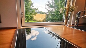 A kitchen with a large window, a stainless steel sink, and a wooden countertop. - Gemütliches Tiny Haus Mitten in der Natur (Fitzen)