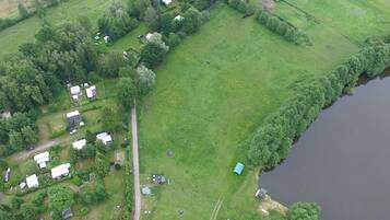 An aerial view of a rural property with several small buildings, a large open grassy area, and a body of water.