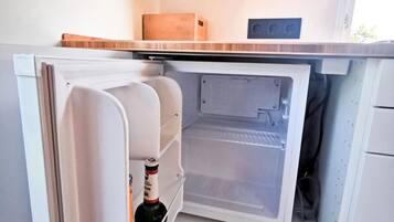 Et kompakt køleskab med frostboks, en lille skuffe og en vinflaske indeni.