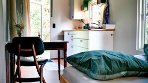 A compact room with a bed, a desk, and a kitchenette. - Gemütliches Tiny Haus Mitten in der Natur (Fitzen)