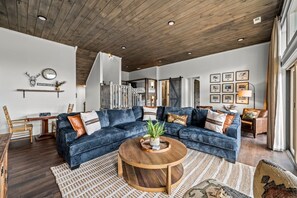 A living room with a dark blue sectional sofa, a wooden coffee table, and a staircase leading to an upper level.