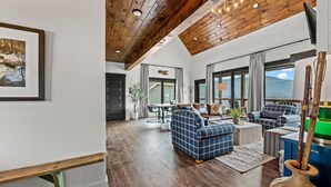 A spacious living area with wooden beams, a fireplace, and large windows.