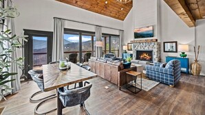 A spacious living area with a fireplace, a dining table, and a view of the outdoors.