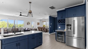Eine moderne Küche mit blauen Schränken, einem Edelstahlkühlschrank und einer großen Kochinsel mit Spüle.