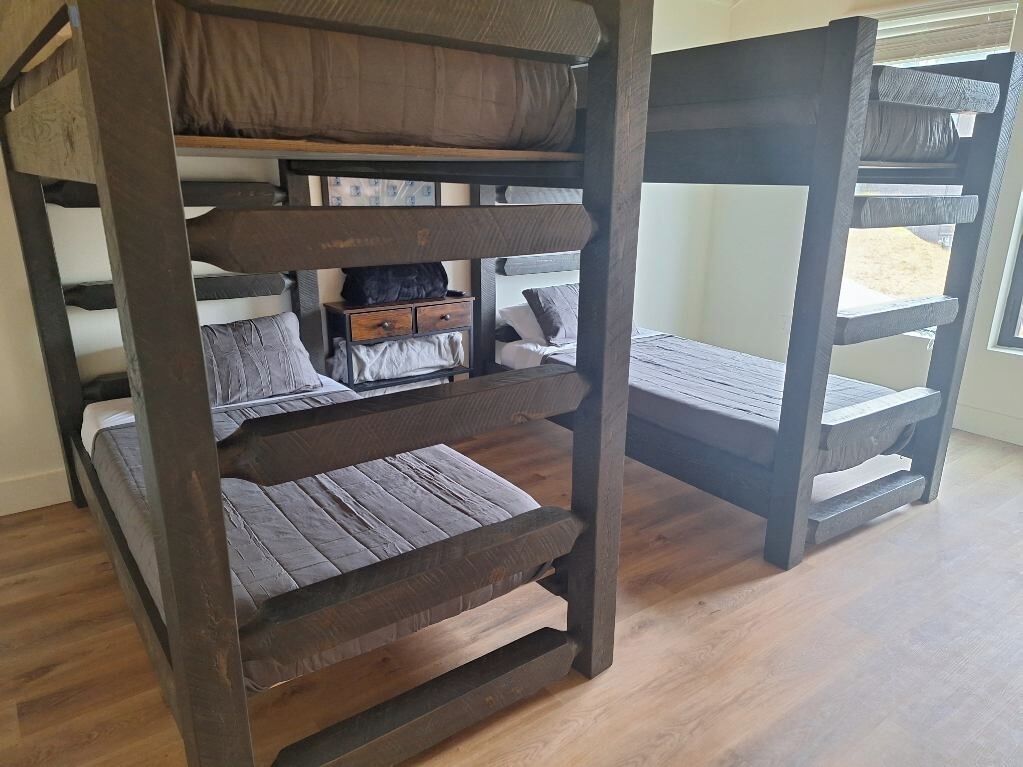 Un lit superposé avec une structure en bois et une literie grise.