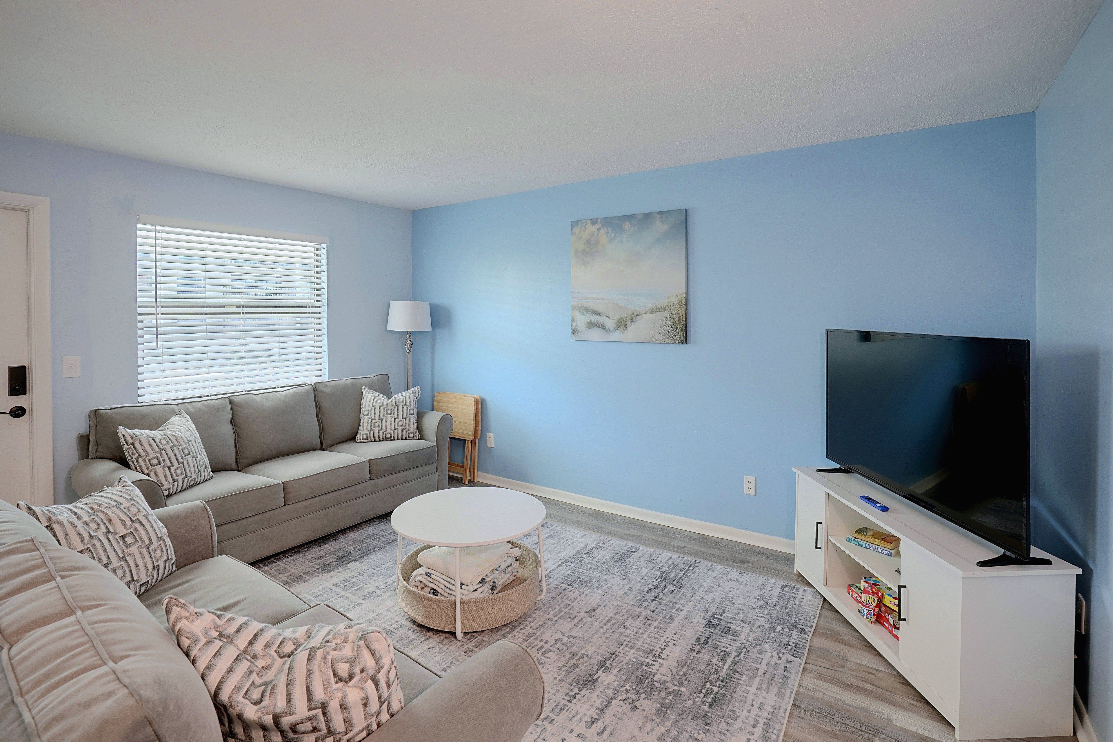 A living room with a sofa, coffee table, TV, and artwork on the wall.