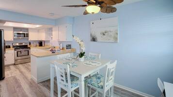 A modern kitchen with a central island, white cabinetry, and a ceiling fan.