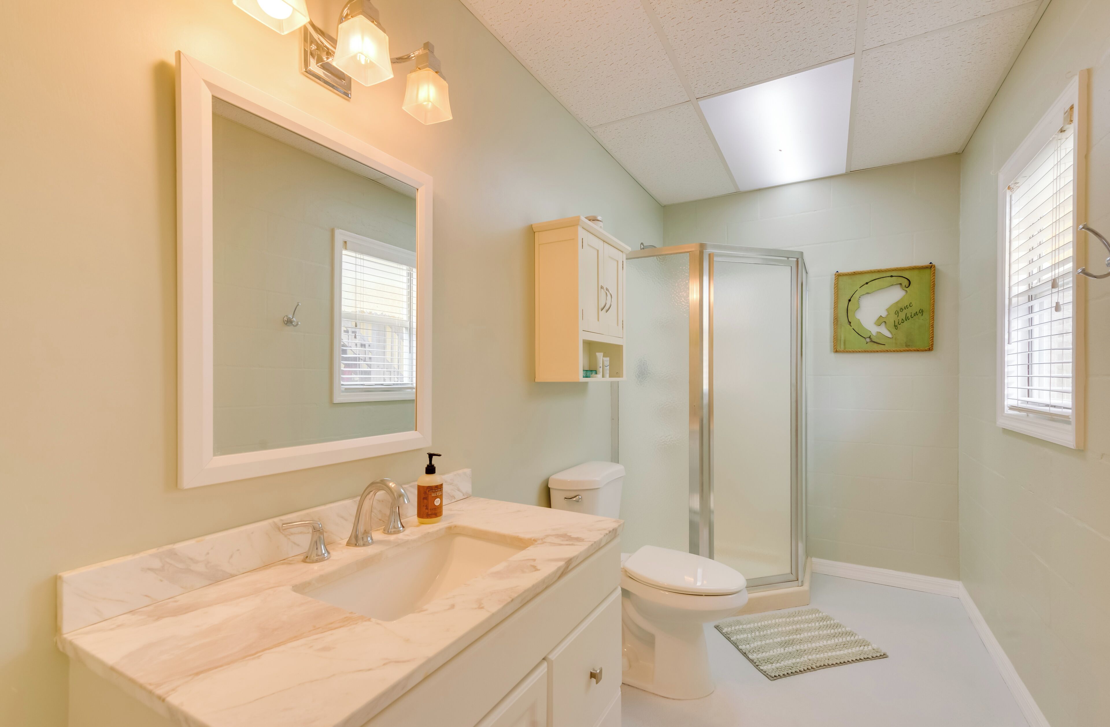 A bathroom with a large mirror, a sink, a toilet, and a shower.