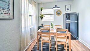 A dining area with a wooden table and chairs, a hanging plant, a refrigerator, and a framed Monopoly board game on the wall. - Family-friendly Clearwater Home w/ Game Room! (Clearwater)
