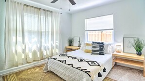 A bedroom with a bed, a ceiling fan, a bedside table with a lamp, and a window with blinds. - Family-friendly Clearwater Home w/ Game Room! (Clearwater)