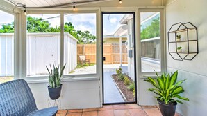 A covered patio with a sliding glass door, potted plants, a chair, and a wall-mounted plant display. - Family-friendly Clearwater Home w/ Game Room! (Clearwater)