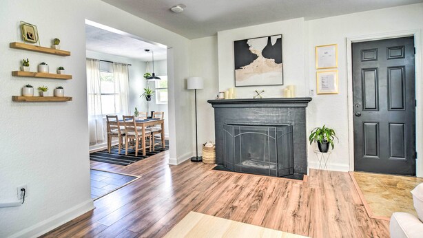 A living room with hardwood flooring, a fireplace, a dining area with chairs, and a door with a dark frame. - Family-friendly Clearwater Home w/ Game Room! (Clearwater)