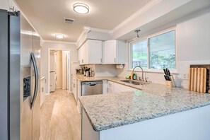 A modern kitchen with granite countertops, white cabinets, and a built-in dishwasher. - Newly Renovated Little Rock Escape w/ Yard! (Little Rock)